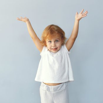 Child in a studio. Little girl on a blue background. Girl in a white t-shirt.