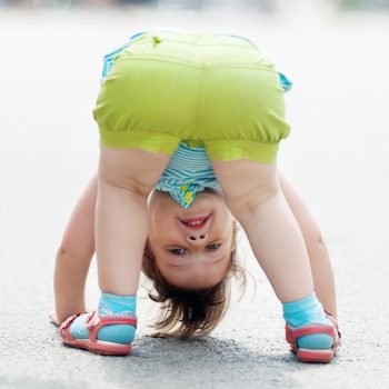three-year baby girl playing upside down in street
